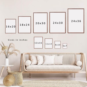 May include: A white wall with various sized picture frames, each with a different measurement listed in inches. The frames are arranged in a row, with the largest frame on the right and the smallest frame on the left. The frames are all white and have a simple, modern design. Below the frames, there is a couch with pillows and a rug on the floor. The text "Sizes in inches" is written below the frames.