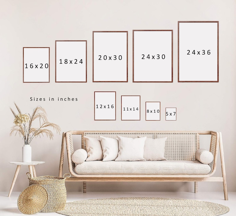 May include: A white wall with various sized picture frames, each with a different measurement listed in inches. The frames are arranged in a row, with the largest frame on the right and the smallest frame on the left. The frames are all white and have a simple, modern design. Below the frames, there is a couch with pillows and a rug on the floor. The text "Sizes in inches" is written below the frames.