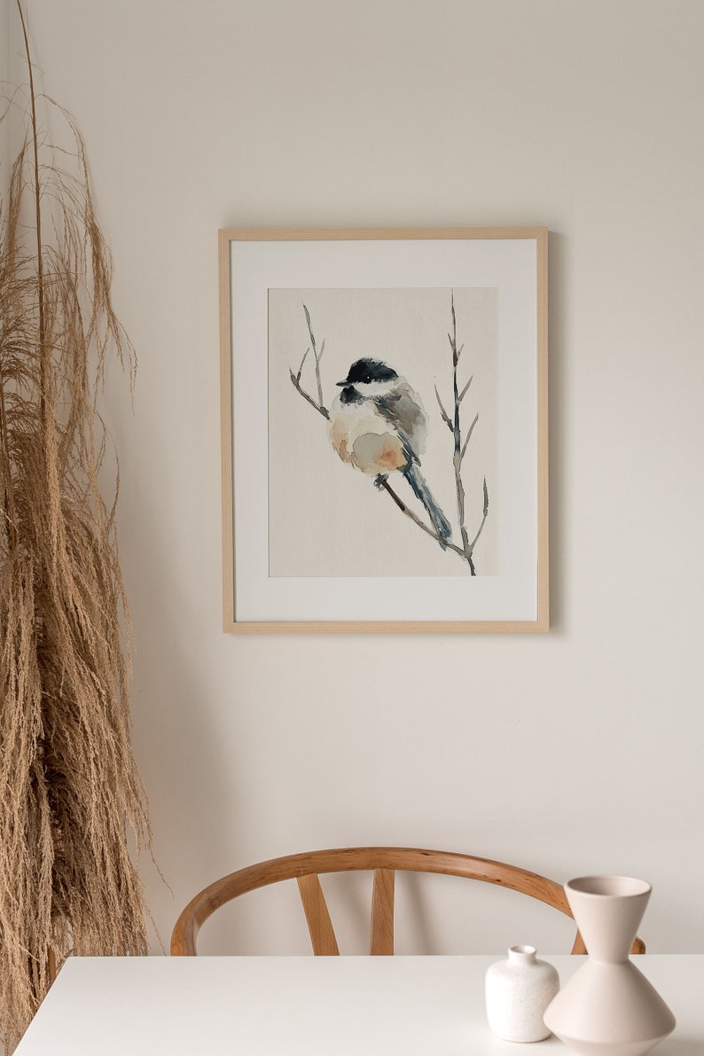 Peut inclure: Une peinture &agrave; l'aquarelle encadr&eacute;e d'un petit oiseau perch&eacute; sur une branche. L'oiseau est gris et blanc avec une t&ecirc;te noire et une longue queue. L'arri&egrave;re-plan est beige clair.