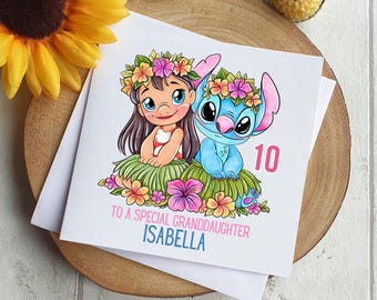 May include: A white card with a cartoon image of Lilo and Stitch. Lilo is wearing a flower lei and a pink dress. Stitch is wearing a blue lei. The card says "To a special granddaughter Isabella" and "10".