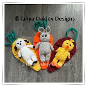 Puede incluir: Tres juguetes de Pascua tejidos: un cordero blanco, un conejito gris y un pollito amarillo. Cada juguete está sobre una base colorida en forma de hoja. El cordero está sobre una base amarilla, el conejito sobre una base naranja y el pollito sobre una base burdeos. El texto "© Tanya Oakley Designs" es visible.