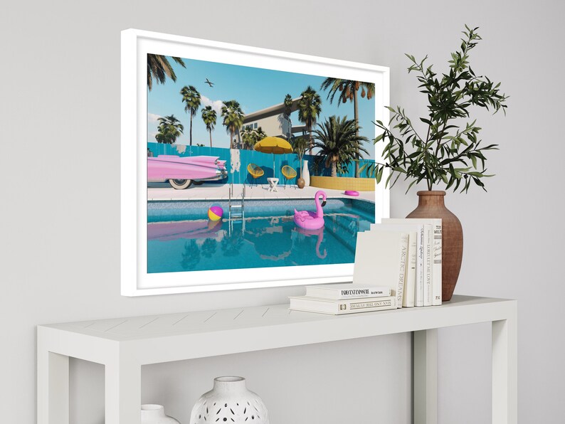 Pu&ograve; includere: Una stampa incorniciata di una casa moderna di met&agrave; secolo con una piscina, palme e un galleggiante a forma di fenicottero rosa. Una Cadillac rosa &egrave; parcheggiata accanto alla piscina.