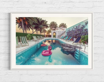 May include: A swimming pool with blue water and a pink flamingo float. There are deckchairs around the pool and palm trees in the background.