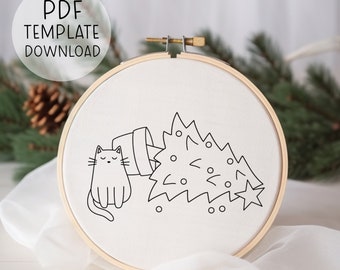 May include: An embroidery hoop with a black and white line drawing of a cat and a tipped-over Christmas tree. The text "PDF TEMPLATE DOWNLOAD" is in a white circle in the upper left.