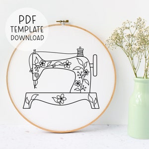 Puede incluir: Un dibujo en blanco y negro de una máquina de coser con detalles florales. La imagen está en un aro y está lista para bordar.