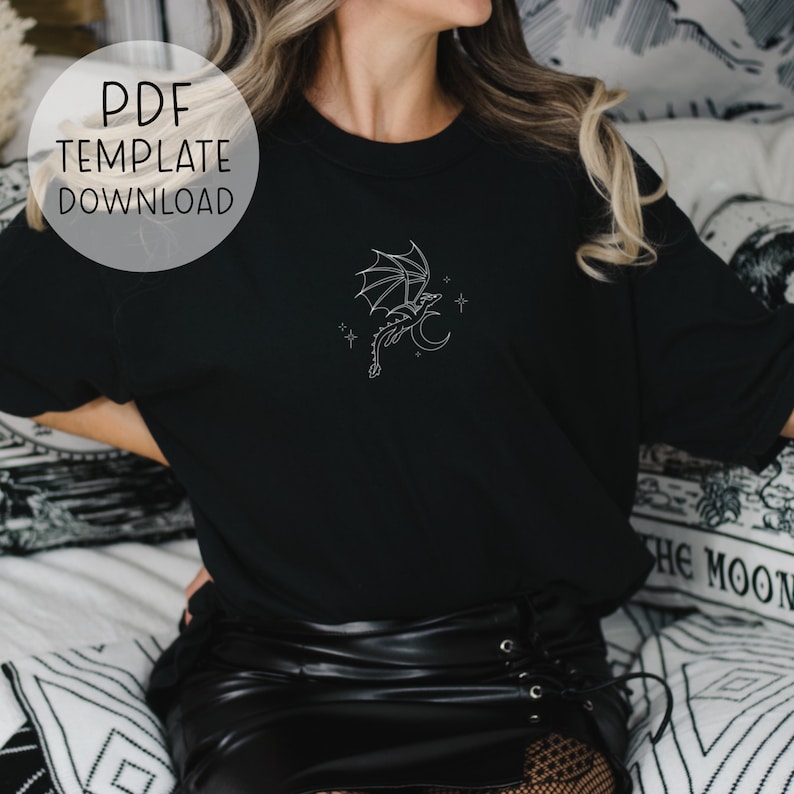 Op de afbeelding: Een zwart T-shirt met een witte omtrek van een draak die over een halve maan met sterren vliegt. De tekst "PDF TEMPLATE DOWNLOAD" staat in een witte cirkel in de linkerbovenhoek van de afbeelding.
