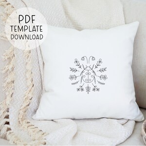 Puede incluir: Una almohada blanca con un dibujo de l&iacute;nea negra de una mariquita rodeada de flores. El texto "PDF TEMPLATE DOWNLOAD" est&aacute; en un c&iacute;rculo en la parte superior izquierda de la imagen.
