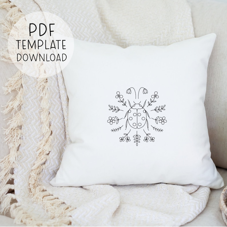 Puede incluir: Una almohada blanca con un dibujo de l&iacute;nea negra de una mariquita rodeada de flores. El texto "PDF TEMPLATE DOWNLOAD" est&aacute; en un c&iacute;rculo en la parte superior izquierda de la imagen.