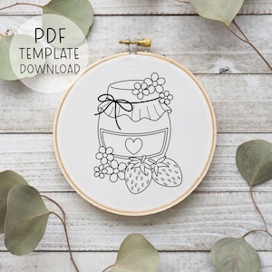 May include: A black and white line drawing of a jar of jam with a heart on the label, surrounded by strawberries and flowers. The image is on a white background and is suitable for embroidery.