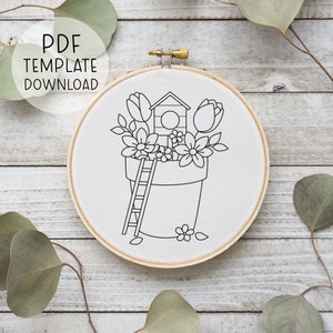 May include: Black and white line art embroidery pattern of a flower pot with a birdhouse on top, surrounded by flowers and a ladder. The pattern is on a white background.
