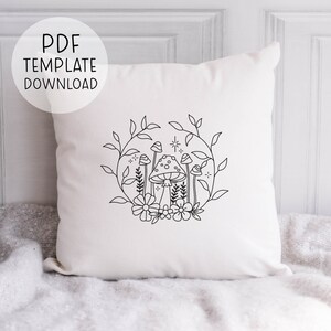 May include: A white cushion featuring a black line drawing of mushrooms and flowers within a circle. The design is simple and minimalist.