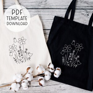May include: Two tote bags with a ghost and flower design. The bag on the left is white with black embroidery. The bag on the right is black with white embroidery. Both bags have the text "PDF TEMPLATE DOWNLOAD" on them.