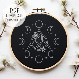 Peut inclure: Un cerceau de broderie noir avec un motif blanc d'un nœud celtique avec deux fleurs et un cercle de lunes autour. Le texte "PDF TEMPLATE DOWNLOAD" est dans le coin supérieur gauche de l'image.