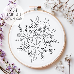 May include: Black and white line drawing of a floral bouquet in a round embroidery hoop. The design features several flowers and leaves.