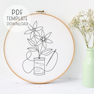 May include: A white embroidery hoop with a floral design and the text "PDF TEMPLATE DOWNLOAD". The design features a spool of thread, needle, and flowers. A light green vase with white flowers is in the background.