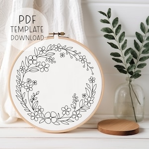 May include: Black and white floral embroidery hoop design with a simple wreath of flowers and leaves.  PDF Template Download.