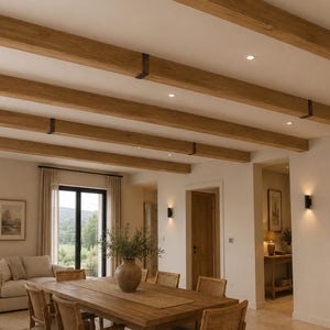 Può includere: Una sala da pranzo con un lungo tavolo in legno e sedie in vimini, pareti dai toni chiari e travi in legno a vista sul soffitto fissate con staffe in metallo scuro. L'illuminazione è fornita da faretti incassati e applique da parete.