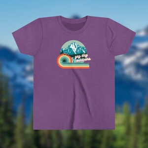 May include: Purple t-shirt with a retro-style graphic of a mountain range and a rainbow with the text "gay day outdoors".