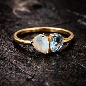 May include: A white ceramic mug with a black handle and the text "But First, Coffee" in a black, handwritten-style font. The mug is on a white surface.