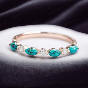 May include: A delicate rose gold band ring with five turquoise stones and small diamonds set in between. The turquoise stones are oval shaped and have a marbled pattern.