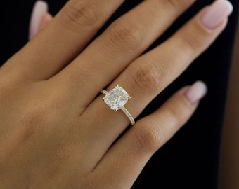 May include: A gold engagement ring with a large, cushion-cut diamond center stone and smaller diamonds set in the band.