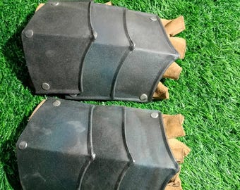 以下が含まれることがあります： 茶色の革のストラップと金属のリベットが付いた、黒い革製の腕のガードのペア