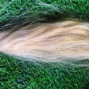 May include: A long, light blonde hair extension. The hair is straight and appears to be very soft.