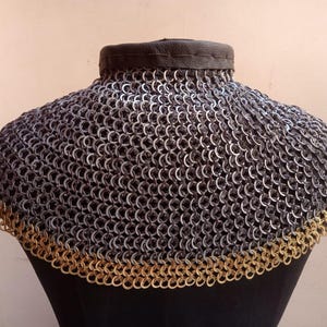 May include: A silver chainmail collar with a gold trim. The collar is made of interlocking metal rings and is designed to protect the neck.