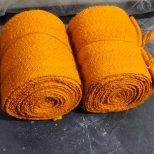 Może przedstawiać: Dwa rolki jasno pomarańczowej tkaniny, prawdopodobnie do rękodzieła lub tapicerki.