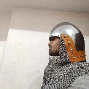 May include: A silver helmet with a brown leather trim and chainmail neck guard. The helmet has a rounded top and a pointed front.