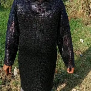 May include: A black chainmail shirt with a v-neck collar. The shirt is made of interlocking metal rings.