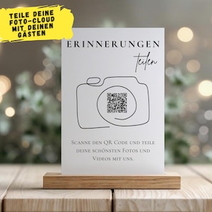 May include: A white card with the word "ERINNERUNGEN" and a camera illustration with a QR code, set in a wooden holder. The card also has the text "TEILE DEINE FOTO-CLOUD MIT DEINEN GÄSTEN" and "SCANNE DEN QR CODE UND TEILE DEINE SCHÖNSTEN FOTOS UND VIDEOS MIT UNS."