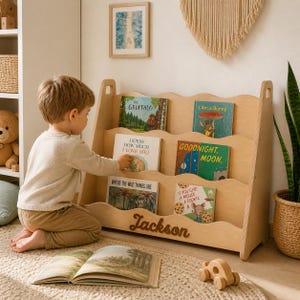 Personalized Montessori bookshelf with name ‘Jackson’, wooden kids book display, toddler boy reading in cozy nursery, front facing book storage for children