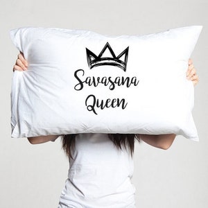 May include: White pillow with black text that reads "Savasana Queen" and a black crown graphic.