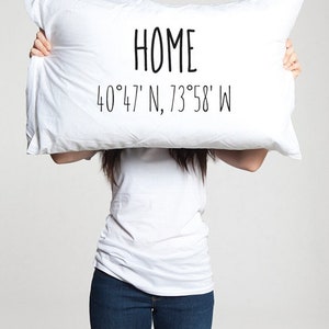 May include: White pillow with black text that reads "HOME 40°47' N, 73°58' W".