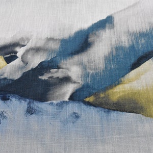 May include: Abstract art print featuring a watercolour-like design with shades of blue, grey, and gold. The print has a textured linen background.