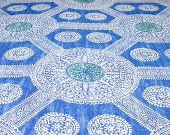May include: A blue fabric with a white and green patterned design. The pattern features repeating circles and floral motifs.