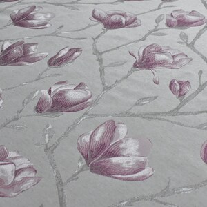 May include: A close-up of a fabric with a repeating pattern of pink magnolia flowers and silver branches on a light gray background.