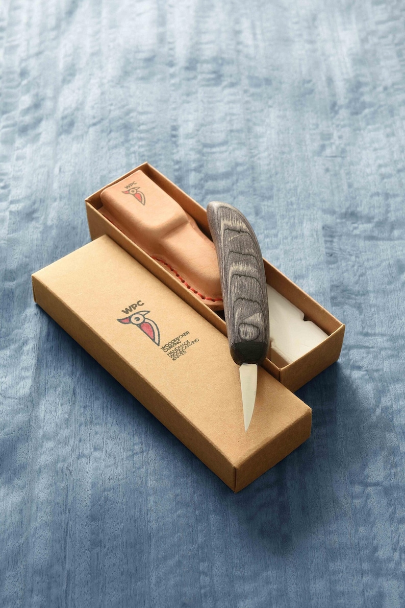 May include: A small, wooden-handled carving knife with a leather sheath in a brown cardboard box. The box has the logo "WPC" and the text "WOODCRAFT PRODUCTS CO. LTD. JAPAN" printed on it.