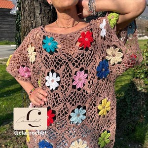 May include: A brown crochet top with vibrant flower embellishments. The top has an open, net-like structure, decorated with flowers in red, blue, yellow, pink, and white. The brand name "Clacrochet" is displayed in the image.
