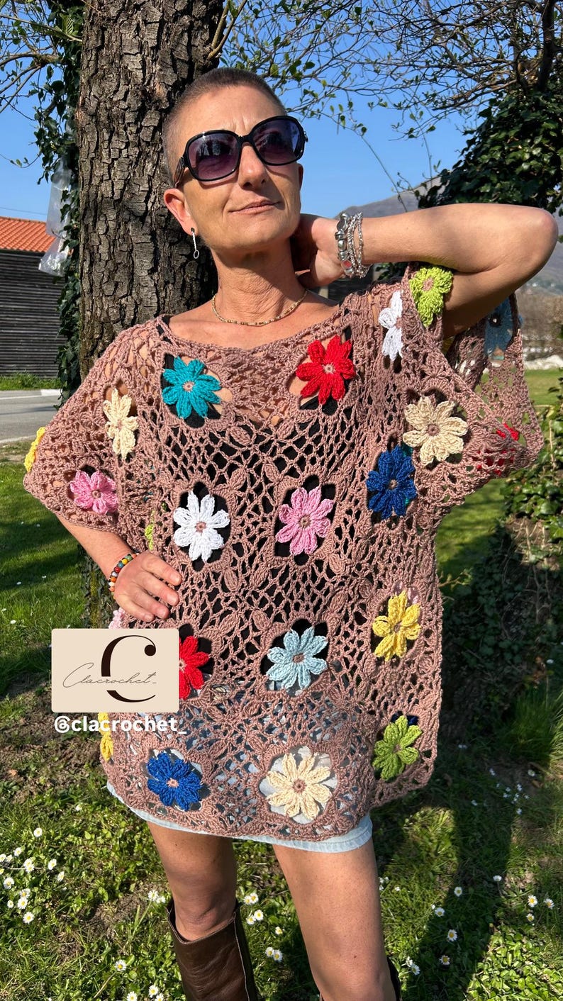 May include: A brown crochet top with vibrant flower embellishments. The top has an open, net-like structure, decorated with flowers in red, blue, yellow, pink, and white. The brand name "Clacrochet" is displayed in the image.