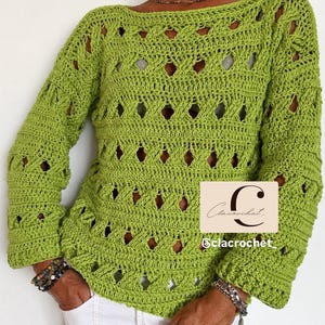 Può includere: Un maglione a maniche lunghe all'uncinetto color verde lime con un motivo traforato a rombi ripetuti e uno scollo a barchetta. Una toppa rettangolare con il testo Clacrochet e @clacrochet è visibile sul lato inferiore destro del capo.