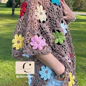 May include: A brown crochet top decorated with vibrant, crocheted flowers in red, yellow, pink, blue, and green. The top features a loose, open weave and short sleeves. The text "C" and "@clacrochet" are visible.