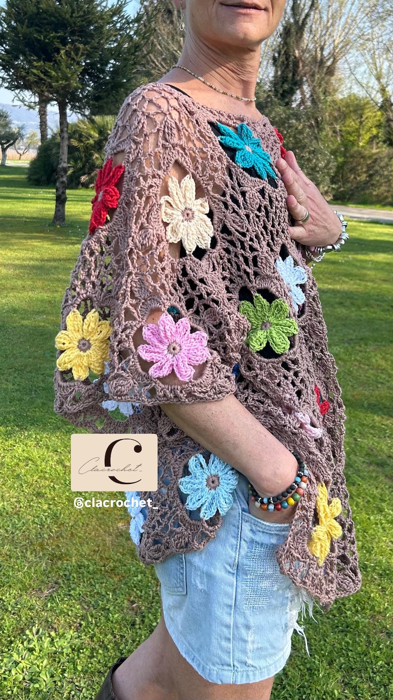 May include: A brown crochet top decorated with vibrant, crocheted flowers in red, yellow, pink, blue, and green. The top features a loose, open weave and short sleeves. The text "C" and "@clacrochet" are visible.