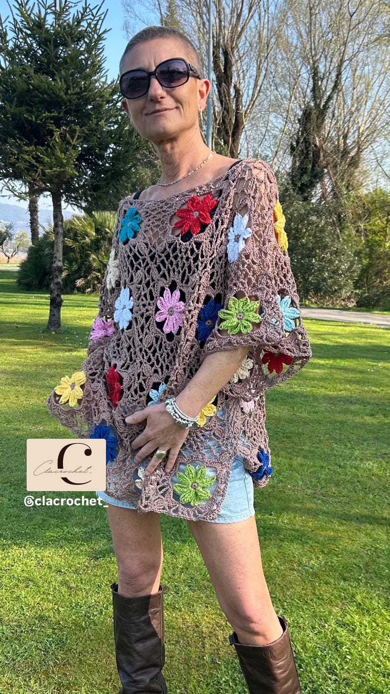 May include: A brown crochet top decorated with vibrant flower appliqu&eacute;s. The top features a loose, open weave and short sleeves. The image also includes the text "C @clacrochet".