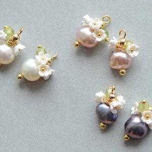 Puede incluir: Cinco abalorios de perla y flor con detalles dorados. Cada abalorio presenta una perla, flores blancas y piedras preciosas verdes.
