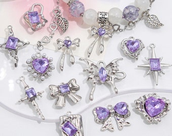 May include: A collection of silver charms with purple crystals. The charms include a cross, a heart, a star, a butterfly, a bow, and a book. The charms are perfect for adding a touch of sparkle to any jewelry project.