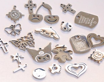 May include: A collection of silver charm pendants featuring various designs, including butterflies, hearts, crosses, cherries, a skull, a bear, a cat, a sun, and a tag that reads "Without chance there would be no butterflies".
