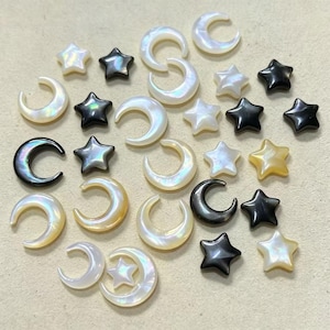 Puede incluir: Una colección de pequeñas piezas decorativas planas con forma de estrellas y lunas crecientes. Los artículos están hechos de materiales iridiscentes blancos, crema y negros sólidos, con superficies lisas y siluetas celestiales.