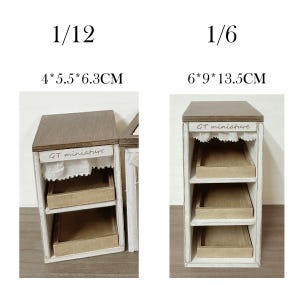 Pu&ograve; includere: Due vetrine in legno in miniatura. Una misura 4 cm x 5,5 cm x 6,3 cm, l'altra 6 cm x 9 cm x 13,5 cm. Ogni vetrina ha un top marrone, una cornice bianca e tre ripiani. Il testo "GT miniature" &egrave; visibile.